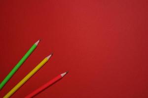 Colored wooden pencils scattered on red background, education concept. photo
