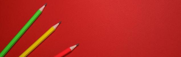 Colored wooden pencils on red background, education concept. photo