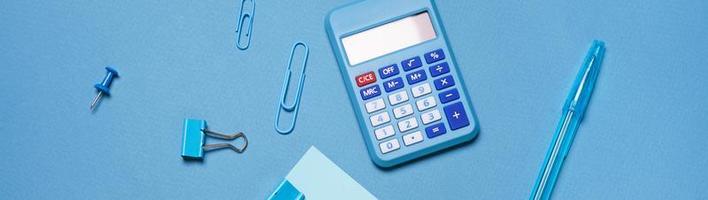 Calculator, stationery accessories on blue background with copy space. Look photo