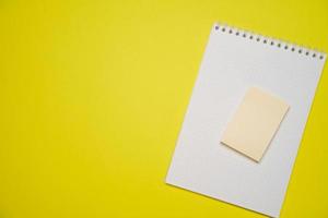 abra el bloc de notas blanco en blanco en una espiral y pegatinas en un fondo amarillo. foto