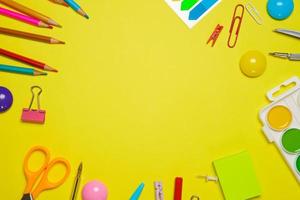 Frame with school supplies on a yellow background. Flat dip, top view. photo