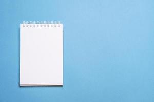 School notebook on blue background, spiral notepad on table, education photo