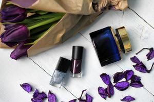 Bouquet of purple tulips, perfume and nail polish on a white table photo