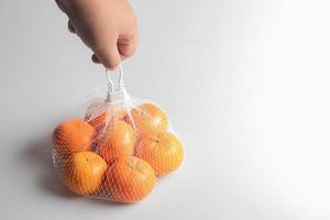 naranjas frescas en una bolsa de malla sobre un fondo blanco. foto