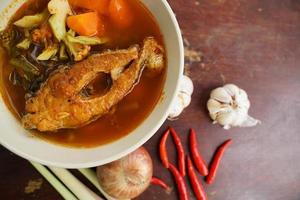 Tamarind curry with fried fish and vegetables on wooden floor - Thai style  That is delicious and has been very popular. photo