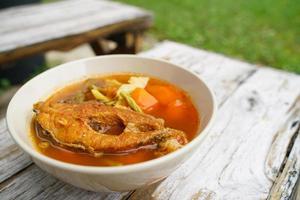 Tamarind curry with fried fish and vegetables on wooden floor - Thai style  That is delicious and has been very popular. photo