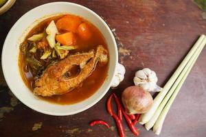 Tamarind curry with fried fish and vegetables on wooden floor - Thai style  That is delicious and has been very popular. photo