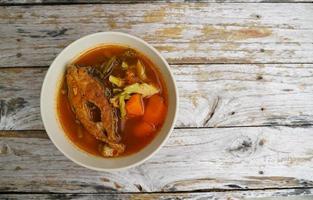 Tamarind curry with fried fish and vegetables on wooden floor - Thai style  That is delicious and has been very popular. photo