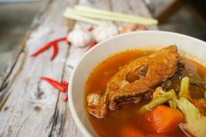 Tamarind curry with fried fish and vegetables on wooden floor - Thai style  That is delicious and has been very popular. photo