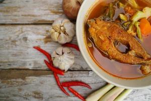 Tamarind curry with fried fish and vegetables on wooden floor - Thai style  That is delicious and has been very popular. photo