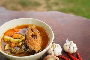 Tamarind curry with fried fish and vegetables on wooden floor - Thai style  That is delicious and has been very popular. photo