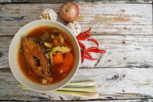 Tamarind curry with fried fish and vegetables on wooden floor - Thai style  That is delicious and has been very popular. photo