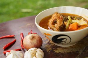 Tamarind curry with fried fish and vegetables on wooden floor - Thai style  That is delicious and has been very popular. photo