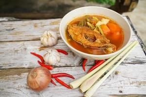 Tamarind curry with fried fish and vegetables on wooden floor - Thai style  That is delicious and has been very popular. photo