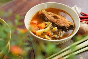 Tamarind curry with fried fish and vegetables on wooden floor - Thai style  That is delicious and has been very popular. photo