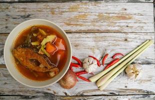Tamarind curry with fried fish and vegetables on wooden floor - Thai style  That is delicious and has been very popular. photo