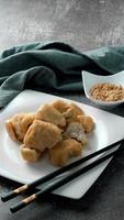 Fried tofu served in a white plate with tamarind sauce and mashed beans, fried tofu is a popular dish among Chinese and Asians. photo