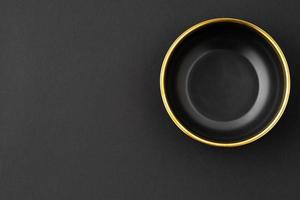 A set of black and golden ceramic bowl on a black background. Top view photo