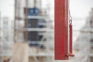 A selective focus of a hanging rail with a hammer for ringing lunch break or the end of the working day at construction with blurred background photo