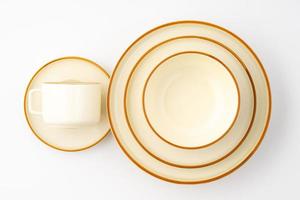 A set of white and brown ceramic plate and cup on a white background. Top view photo