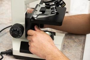 un primer plano de una persona usando un microscopio en un laboratorio médico foto