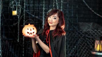 Asian beautiful woman model dressed as a witch costume smile and holding pumkin in halloween theme. photo