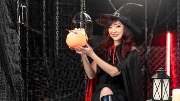 Beautiful young woman in witch costume holding halloween pumpkin in  halloween theme. photo