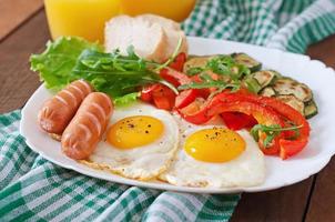 English breakfast - fried eggs, sausages, zucchini and sweet peppers photo