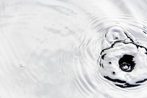 gotitas de agua o gotas de agua caen sobre la superficie del agua causando que la superficie del agua se disperse y forme espuma. foto