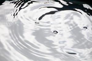 gotitas de agua o gotas de agua caen sobre la superficie del agua causando que la superficie del agua se disperse y forme espuma. foto