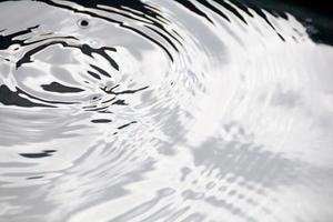 gotitas de agua o gotas de agua caen sobre la superficie del agua causando que la superficie del agua se disperse y forme espuma. foto