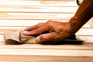 trabajando para alisar la madera y limpiar con papel de lija foto