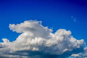 nubes blancas, flotando y formándose con un cielo azul en el fondo foto