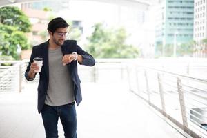 el hombre de negocios sosteniendo una taza de café y mirando el reloj mientras se apresura a ir a trabajar en la hora pico. foto