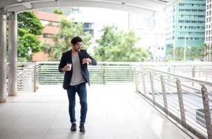 el hombre de negocios sosteniendo una taza de café y mirando el reloj mientras se apresura a ir a trabajar en la hora pico. foto