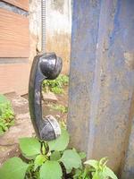 an old type of telephone handle isolated in an abandoned park. a type of telephone era in 1990 photo