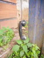 an old type of telephone handle isolated in an abandoned park. a type of telephone era in 1990 photo