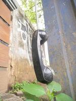 an old type of telephone handle isolated in an abandoned park. a type of telephone era in 1990 photo