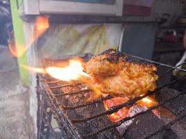 pechuga de pollo envuelta en harina crujiente con deliciosos condimentos picantes a la parrilla sobre carbón caliente.comida típica de pollo a la parrilla de indonesia foto