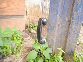 an old type of telephone handle isolated in an abandoned park. a type of telephone era in 1990 photo