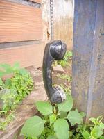 an old type of telephone handle isolated in an abandoned park. a type of telephone era in 1990 photo