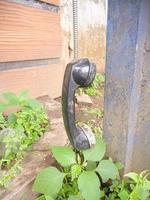 an old type of telephone handle isolated in an abandoned park. a type of telephone era in 1990 photo