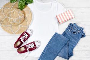 T shirt white and sneakers. T-shirt Mockup flat lay with summer accessories. Hat, jeans and sneakers on wooden floor background. Copy space. Template blank canvas. Front top view. photo