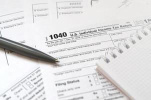 The pen and notebook is lies on the tax form 1040 U.S. Individual Income Tax Return. The time to pay taxes photo