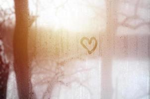 The heart is painted on the misted glass in winter photo