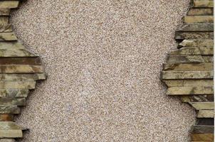 Plastered concrete wall with a frame of flat stones photo