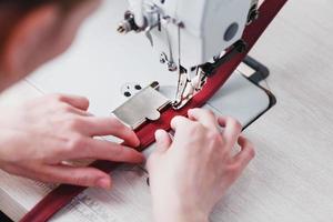 A leather craftsman produces leather goods on a sewing machine in his shop. photo