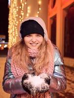 Happy smiling young Caucasian woman in scarf, hat, jacket, mittens at winter night outdoor. New year, fun, winter concept photo