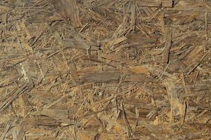 Old OSB boards are made of brown wood chips sanded into a wooden background. Top view of OSB wood veneer chipboard background, tight, seamless surfaces photo