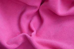 The blanket of furry pink fleece fabric. A background of light pink soft plush fleece material with a lot of relief folds photo